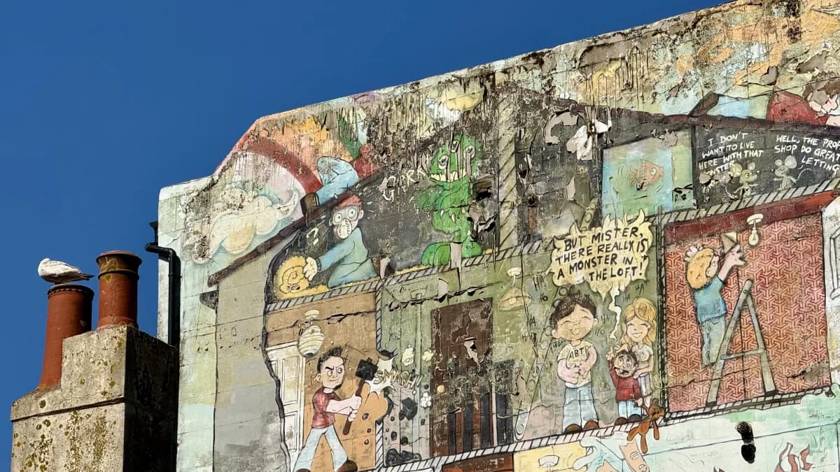 A multi-panel weathered mural on the gable end of a Kemptown building