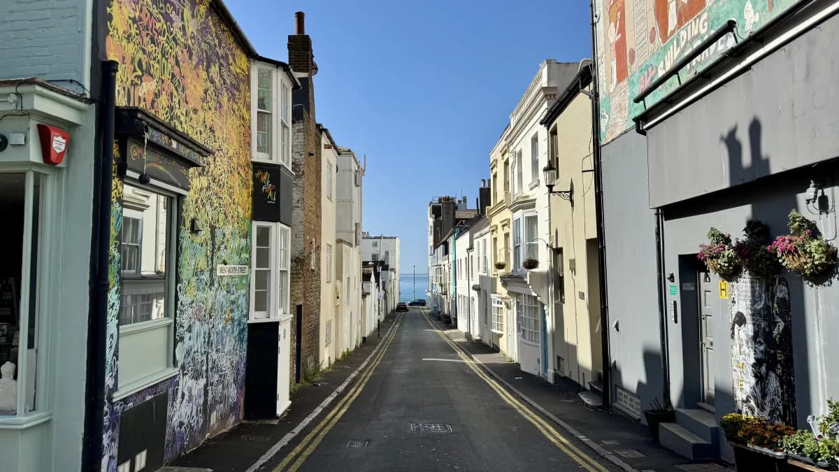 A narrow Kemptown side street lined with painted shopfronts, looking towards the sea