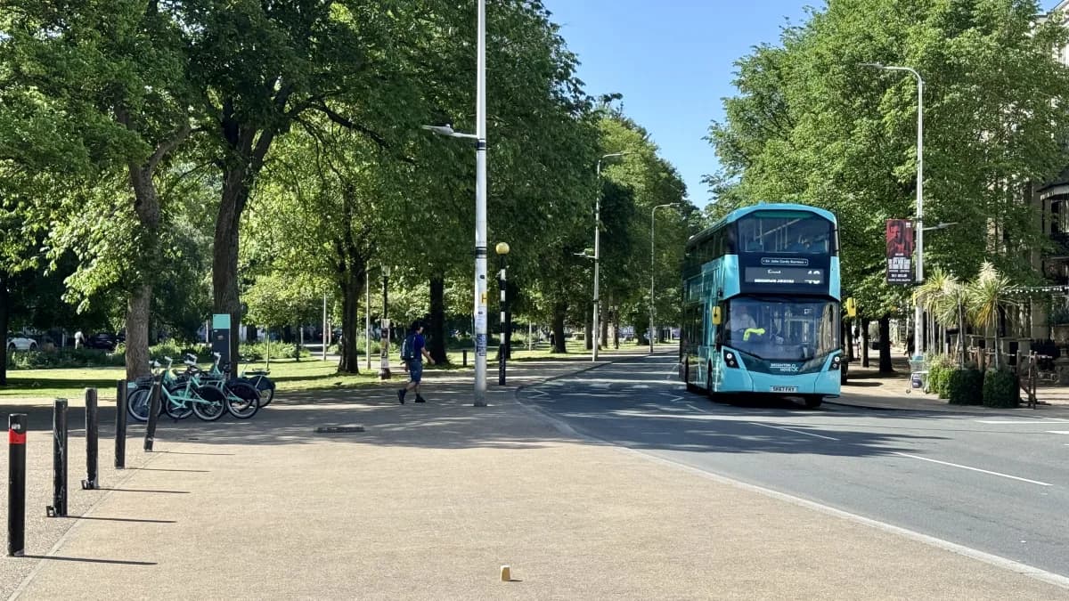 A double-decker bus passing along a tree-lined Valley Gardens with a public bike rack in the foreground