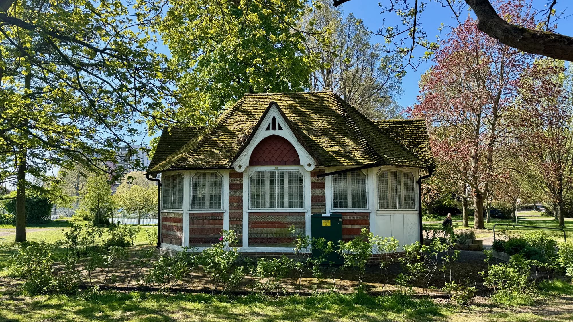 The Preston Park pavilion building with its tile roof and red-and-cream façade among trees in spring