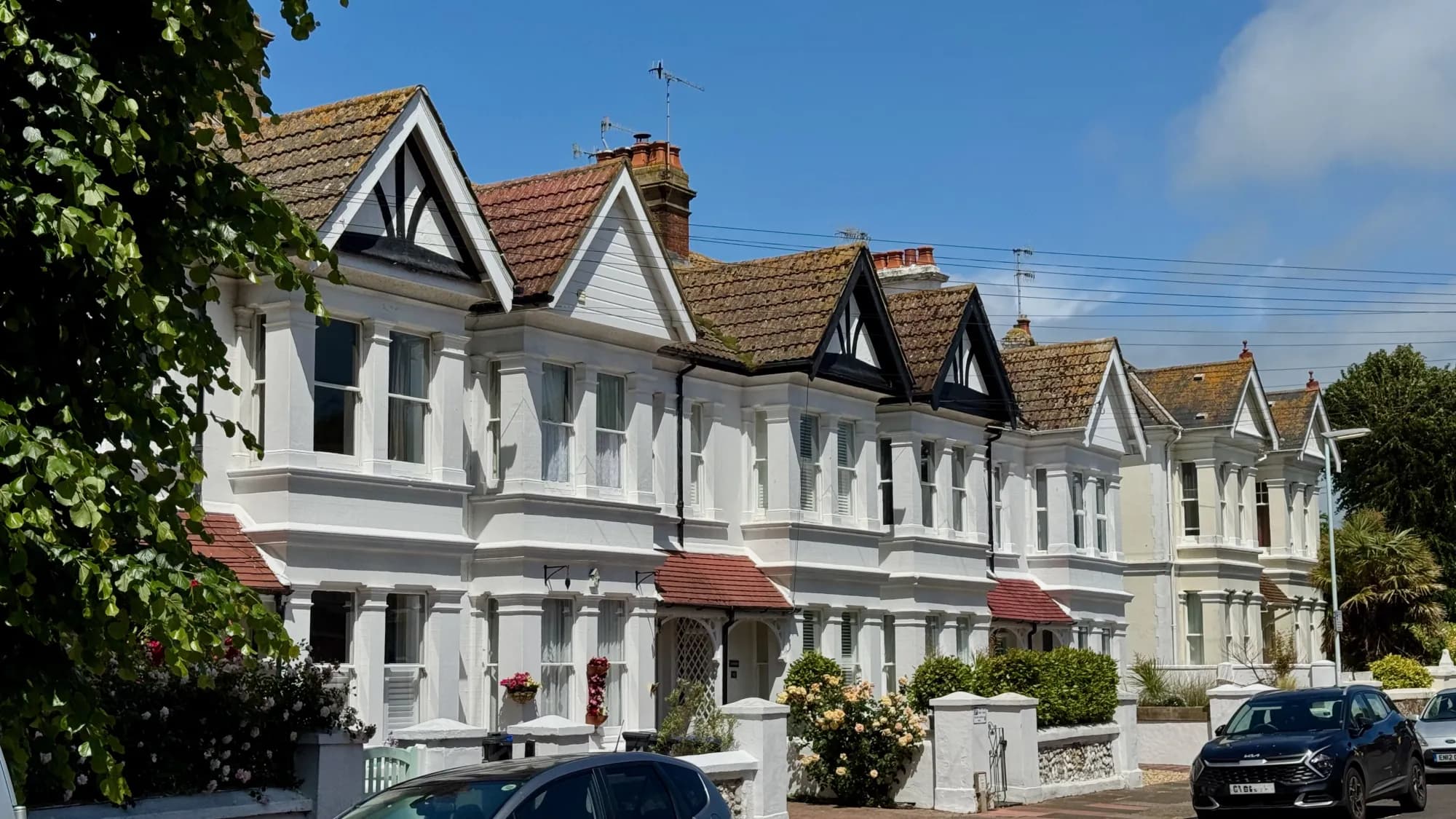A row of white-rendered Edwardian terraces with gabled roofs