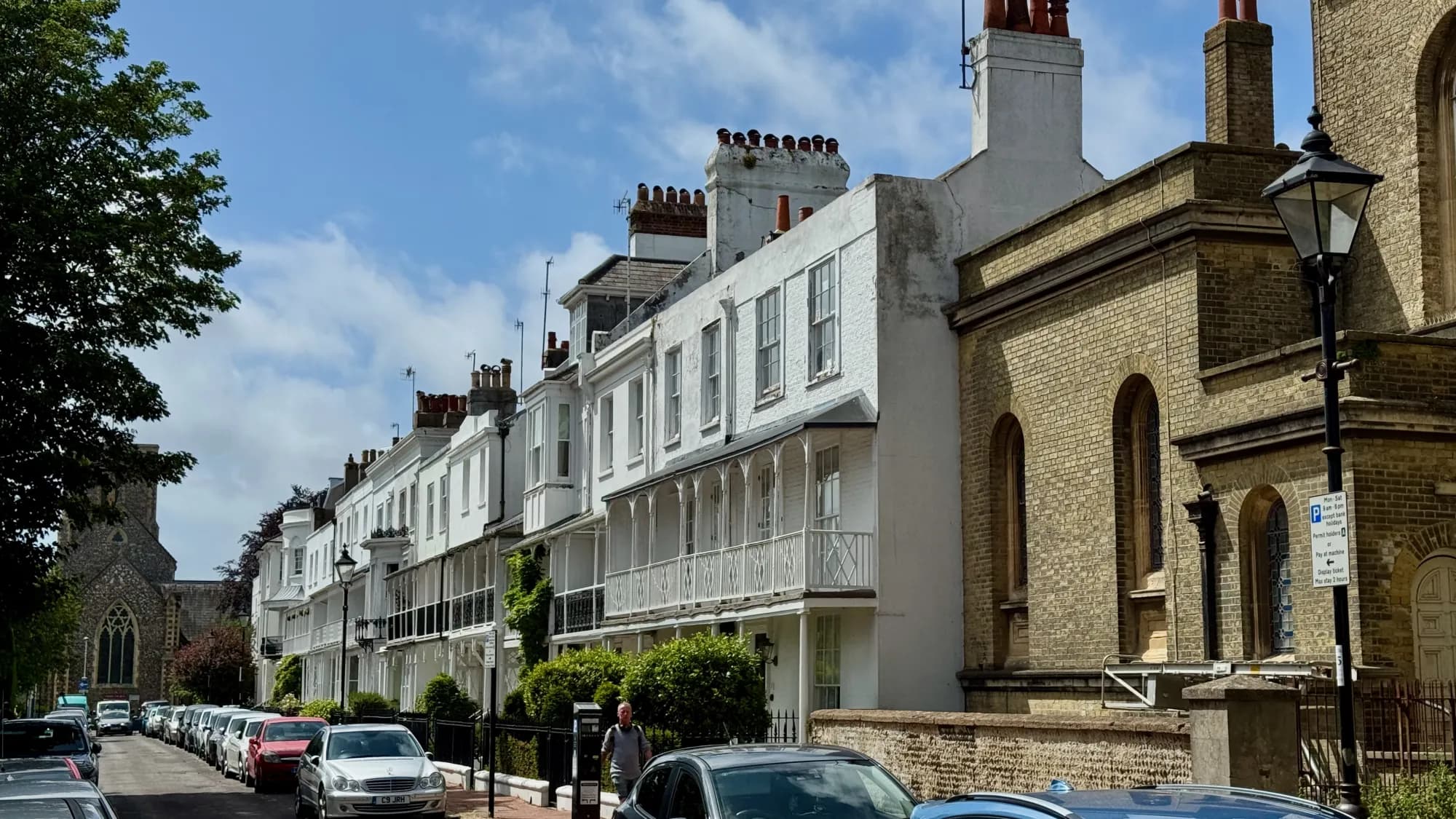 A Regency terrace with cast-iron verandahs running down a town-centre street beside a church