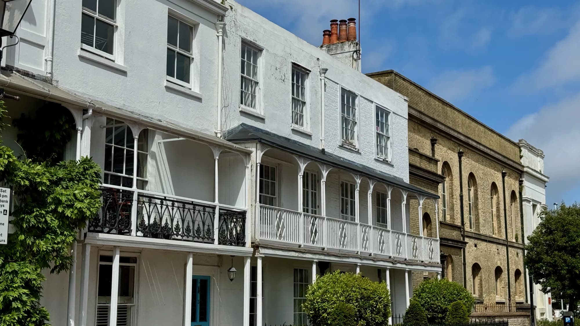A white-painted Regency verandah terrace next to older stone buildings in the town centre