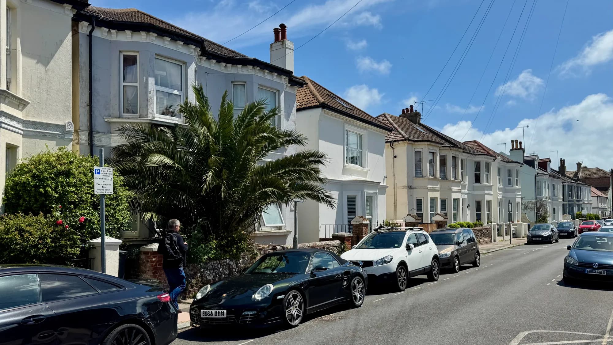 White-rendered Victorian terraces and a palm tree on a sunny town-centre side street